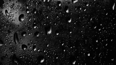 Islak cam. Su damlacıkları. Kapalı camlara yağmur damlaları düşer. Seçici odak siyah ve beyaz
