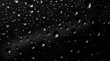 Islak cam. Su damlacıkları. Kapalı camlara yağmur damlaları düşer. Seçici odak siyah ve beyaz