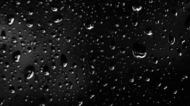 Islak cam. Su damlacıkları. Kapalı camlara yağmur damlaları düşer. Seçici odak siyah ve beyaz