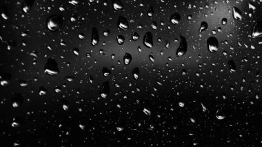 Islak cam. Su damlacıkları. Kapalı camlara yağmur damlaları düşer. Seçici odak siyah ve beyaz