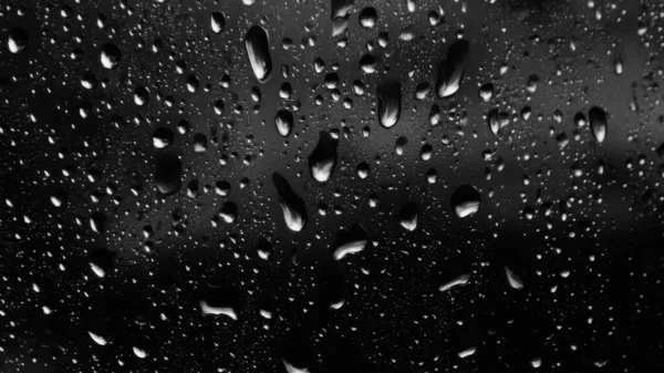 Islak cam. Su damlacıkları. Kapalı camlara yağmur damlaları düşer. Seçici odak siyah ve beyaz