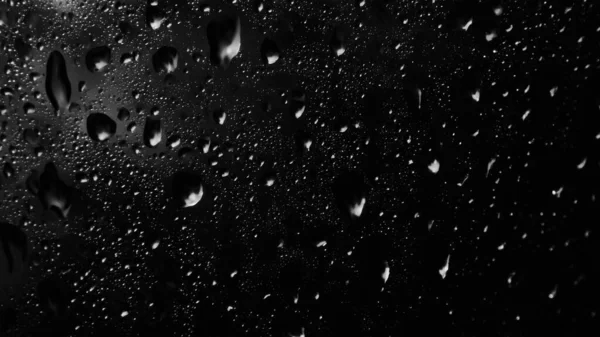 Islak cam. Su damlacıkları. Kapalı camlara yağmur damlaları düşer. Seçici odak siyah ve beyaz
