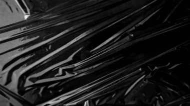 Plastik ambalaj dokusu siyah arkaplan üzerinde kaplama etkisi. Gizlenmek için plastik kolları küçült. Beyaz plastik