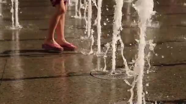 Mouvement lent des jets de fontaine d'eau de plancher avec la personne marchant vers eux — Video