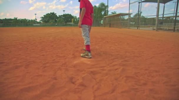 Cool steadicam shot of kid running to first base on baseball field. Shot from behind him — Stock Video