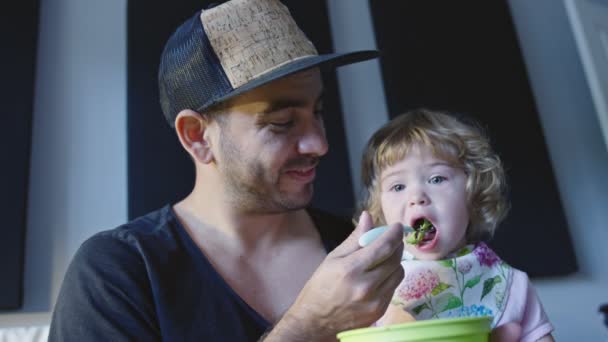 Father feeding broccoli to his baby daughter — Stock Video