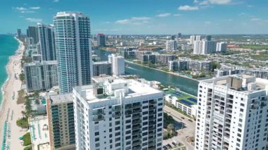Aerial drone footage of Hollywood Beach, Florida, featuring oceanfront buildings, a vibrant coastline, and turquoise waters under a clear sunny sky. Ideal for travel, real estate, or tourism projects.