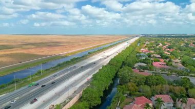 Aerial drone footage of a highway running through Coral Springs, Florida, surrounded by suburban neighborhoods and greenery, ideal for transportation, infrastructure, or travel projects.