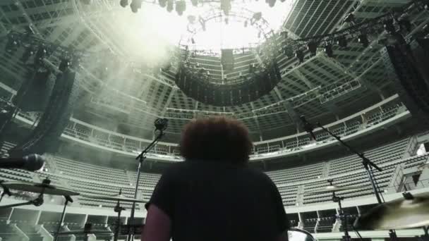 Un hombre tocando la batería en un Coliseo vacío. Fotografía tomada desde el escenario . — Vídeos de Stock