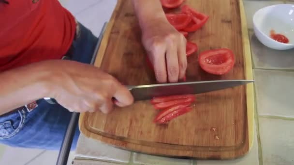 Жіночий шеф-кухар нарізає помідор шматочками — стокове відео