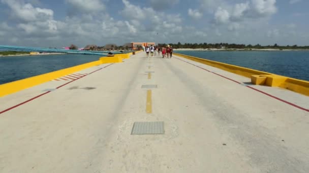 Människor går mot en ö på en gågata mitt i oceanen — Stockvideo