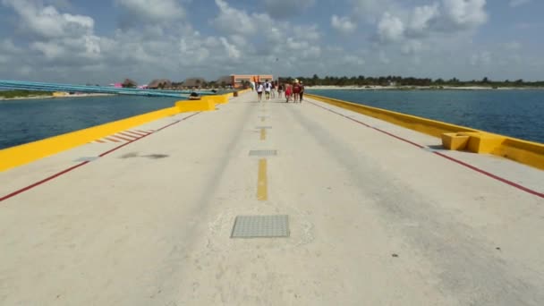 Pessoas caminhando em direção a uma ilha em uma rua pedonal no meio do oceano — Vídeo de Stock