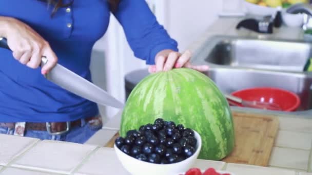 Eine Frau schneidet und öffnet eine Wassermelone — Stockvideo