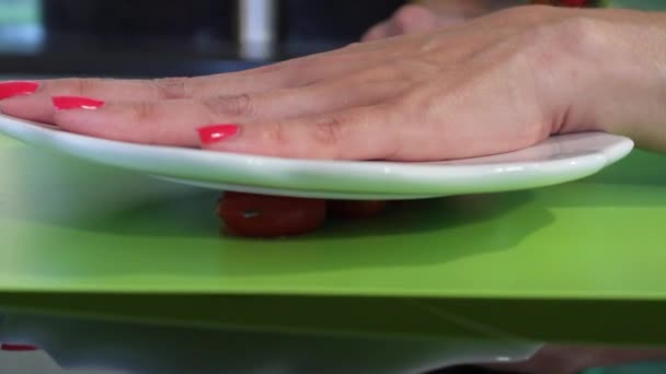 Жіночі руки над тарілкою, коли вона ріже вишневі помідори — стокове відео