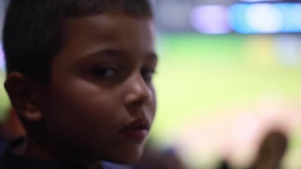 Lindo niño en el estadio de béisbol mirando a la cámara y luego al juego — Vídeos de Stock