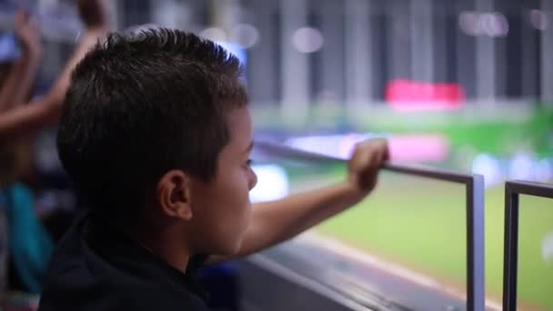 Мила дитина дивиться гру з трибун на стадіоні — стокове відео