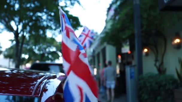 Bandera de Inglés ondeando en una calle con gente que pasa por — Vídeos de Stock