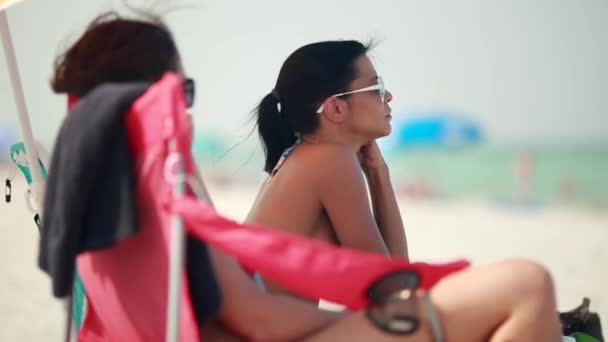 Due donne sedute in spiaggia in una bella giornata — Video Stock