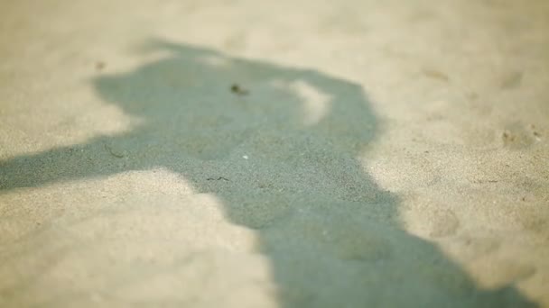 Schatten einer Frau auf dem Sand, während sie sich bewegt und mit Hut spielt — Stockvideo