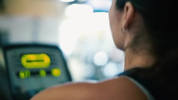 Profil einer Frau, die im Fitnessstudio an einem Crossgerät trainiert — Stockvideo