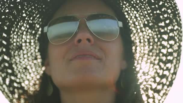 Mujer feliz con sombrero mirando al océano, reflejo visto a través de sus gafas de sol — Vídeos de Stock