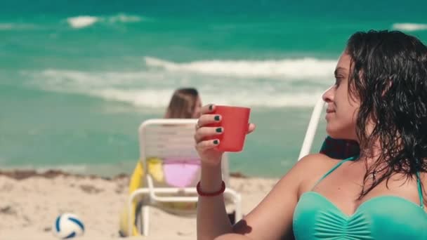 Slow motion van vrouw drankje op een mooi strand door zee — Stockvideo