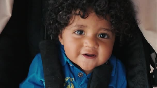 Dziecko z kręconych włosów patrząc na kamery i uśmiechając się — Wideo stockowe