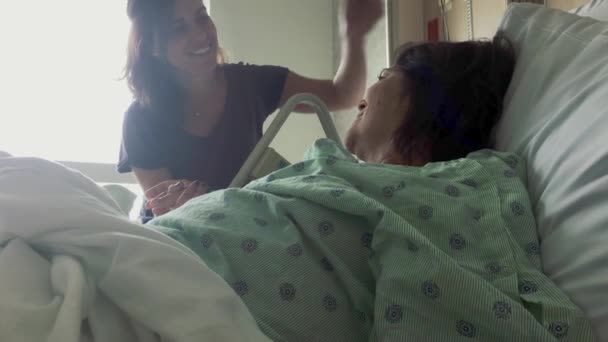 Las manos del hombre sosteniendo las manos de las mujeres mientras ella se acuesta en la cama del hospital — Vídeo de stock