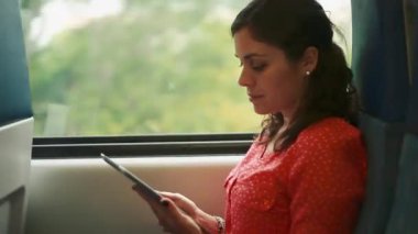 Hareket eden bir trenin içinde bir tablet kullanan kadın