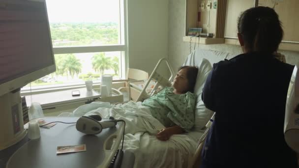 Mulher deitada na cama do hospital com enfermeira trabalhando dentro da sala por gotejamento iv — Vídeo de Stock