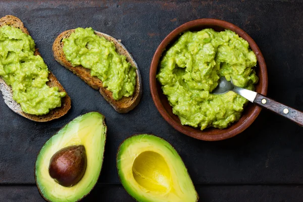 Latin-amerikai mártás guacamole, a avokádó és szendvicsek a sötét háttér. — Stock Fotó