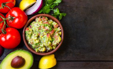 Guacamole ve malzemeler - avokado, domates, soğan, kişniş koyu arka plan.