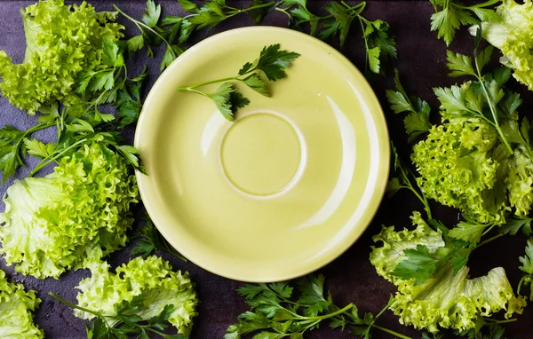Свіжі трави салат навколо зеленої тарілки на чорному фоні — стокове фото
