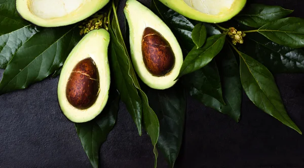 Verse avocado met bladeren op zwarte achtergrond — Stockfoto