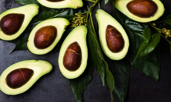 Verse avocado met bladeren op zwarte achtergrond — Stockfoto