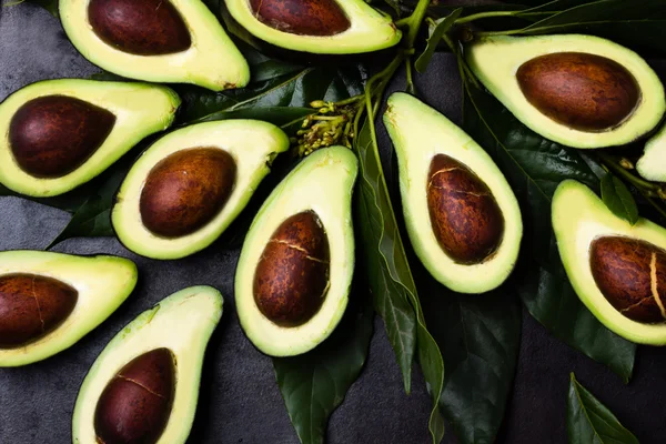 Verse avocado met bladeren op zwarte achtergrond — Stockfoto