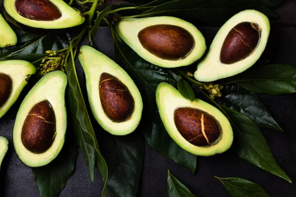 Verse avocado met bladeren op zwarte achtergrond — Stockfoto