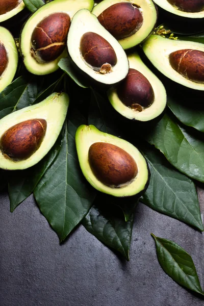 Verse avocado met bladeren op zwarte achtergrond — Stockfoto