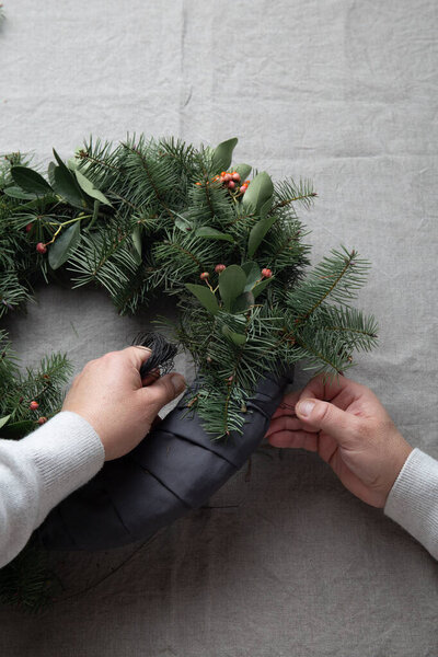 Человек делает рождественский венок. Новогоднее украшение