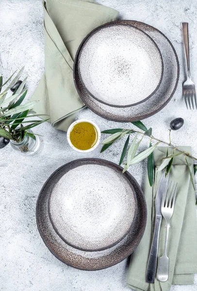 Tavola mediterranea. Piatti grigi, forchette, tovaglioli verdi e rami d'ulivo — Foto Stock