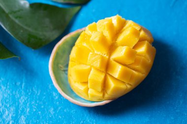 Mavi arka planda mango dilimi, tropikal konsept