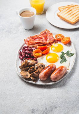 İngiliz kahvaltısı omlet, sosis, pastırma, fasulye, tost, domates ve mantarlı beyaz tabak, somut arka plan, Top view