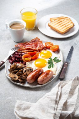 İngiliz kahvaltısı omlet, sosis, pastırma, fasulye, tost, domates ve mantarlı beyaz tabak, somut arka plan, Top view