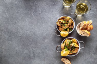 Kişniş, limon ve beyaz şaraplı midyeler gri arka planda küçük tavalar, üst manzara