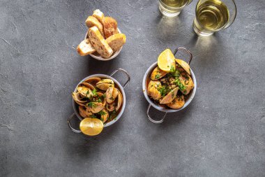 Kişniş, limon ve beyaz şaraplı midyeler gri arka planda küçük tavalar, üst manzara