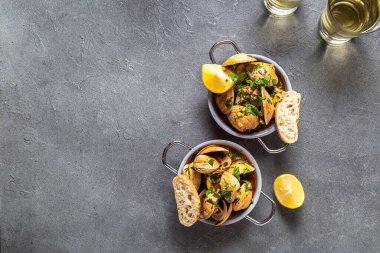 Kişniş, limon ve beyaz şaraplı midyeler gri arka planda küçük tavalar, üst manzara