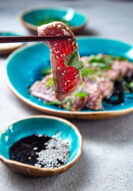 Mavi tabakta soslu ve susamlı biftek tataki. Japon yemeği.