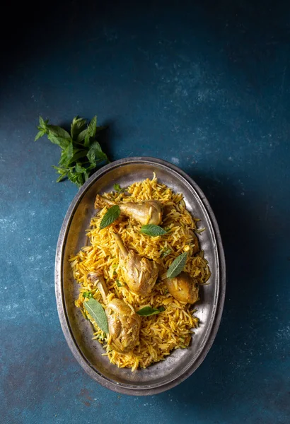 金属の上面にヨーグルトとミントがのったチキンビリヤニライス。パキスタン料理とインド料理 — ストック写真