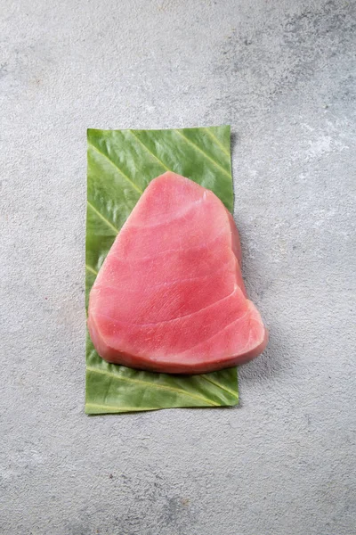 Raw tuna steak on green leaf, grey background — Stock Photo, Image