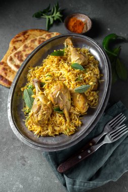 Hint ya da Pakistan yemekleri. Chiken Biryani pilav birası. Nane yeşili ve gri arka planda naan ekmeği.